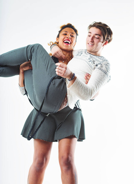 Inversión lúdica como una mujer joven sostiene a un hombre en sus brazos, ambos compartiendo risas alegres en un momento animado - Foto, imagen