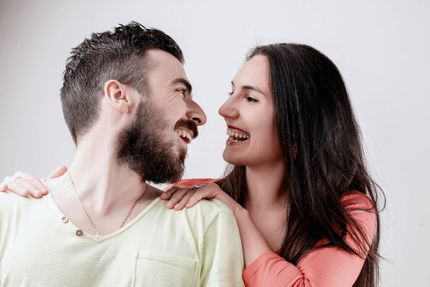 Fröhliches Paar in legerer Kleidung genießt einen verspielten Moment, wobei der Mann seine Arme um die Frau wickelt - Foto, Bild