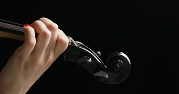 En un bacground negro, vestido de negro, de derecha a izquierda primer plano sobre violín eléctrico negro tocado por manos de un violinista rubio - Metraje, vídeo