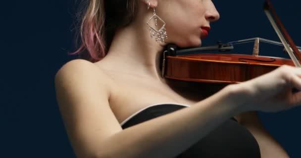 sartén horizontal de izquierda a derecha de tres cuartos de vista desde arriba en un violinista clásico con pelo rosa y hombros desnudos en un vestido de concierto negro - Metraje, vídeo
