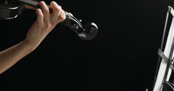 En un bacground negro, vestido de negro, de derecha a izquierda sobre violín electrico negro tocado por violinista rubio - Metraje, vídeo