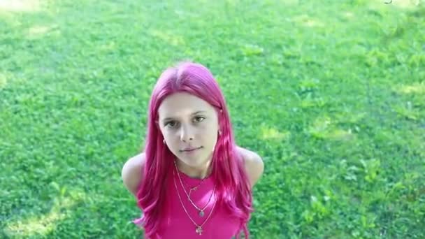 plano aéreo acercándose a una hermosa joven con el pelo rosa y la parte superior, al aire libre en un parque de la ciudad, la vida amorosa - Metraje, vídeo