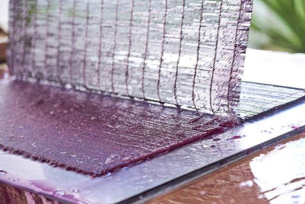 Процесс изготовления фиолетового листа бумаги ручной работы из натуральных волокон и красителей. - Фото, изображение