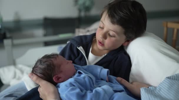 Jonge jongen interactie met zijn pasgeboren broertje tijdens de eerste dag van het leven van de baby in het ziekenhuis kliniek na de bevalling, authentieke broer of zus initiële relatie samen - Video
