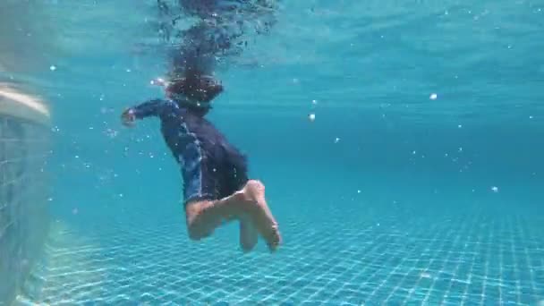 милий хлопчик плаває в басейні, поверхня води з сонячним світлом - Кадри, відео