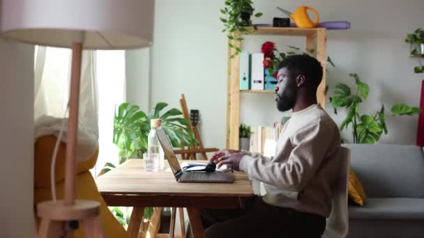 El hombre afroamericano se toma un momento para relajarse, con los ojos cerrados, en un ambiente sereno de oficina en casa rodeado de plantas. - Metraje, vídeo