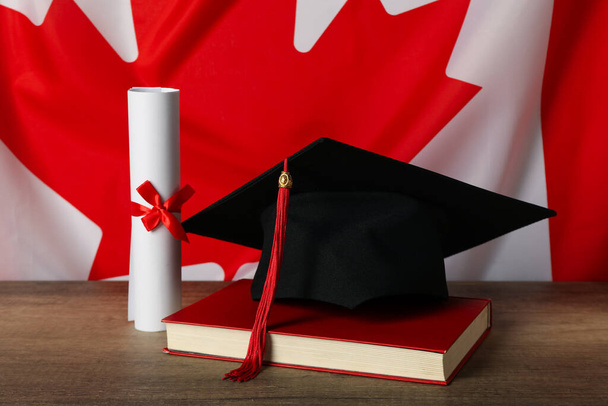 カナダ国旗の背景にある卒業帽子,書籍,卒業証書. - 写真・画像
