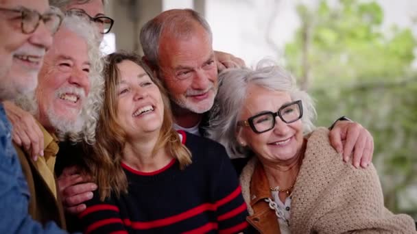 Fröhliche Senioren posieren für ein Foto und lachen zusammen in der Cafeteria. Ältere, gut gelaunte Freunde mit grauen Haaren umarmen sich. Lebensfreude reift mit Spaß im Pflegeheim - Filmmaterial, Video