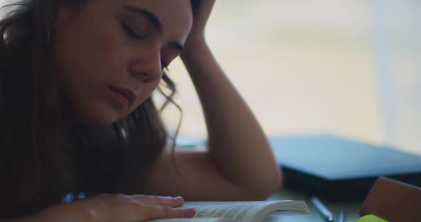 Väsynyt naispuolinen opiskelija uupunut, nukahtaa kirjoja oppimisen aikana - Materiaali, video