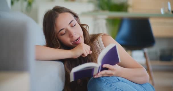 Βαρετή και κουρασμένη φοιτήτρια ενώ διάβαζε βιβλίο - Πλάνα, βίντεο