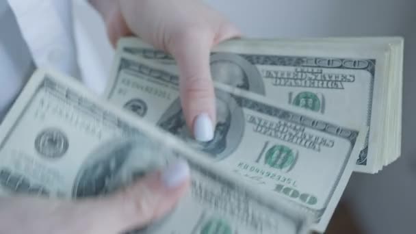 This image features a close-up view of a womans hands as she counts U.S. dollar bills from a stack, emphasizing careful financial handling and savings - Footage, Video