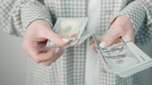 Close-up van een zakenvrouw in een geruite jas, vakkundig omgaan met meerdere US dollar biljetten, nadruk op financieel succes en persoonlijke rijkdom - Video