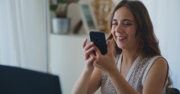 Pozytywna kobieta uśmiecha się i robi zakupy online na smartfonie - Materiał filmowy, wideo
