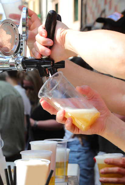 barman hand schenkt vers bier in een glas tijdens een dorpsfeest - Foto, afbeelding