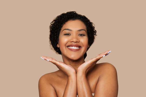 Een Braziliaanse vrouw staat met haar handen voor haar gezicht te poseren voor de camera. Ze straalt zelfvertrouwen en evenwicht uit terwijl ze haar unieke stijl laat zien. - Foto, afbeelding