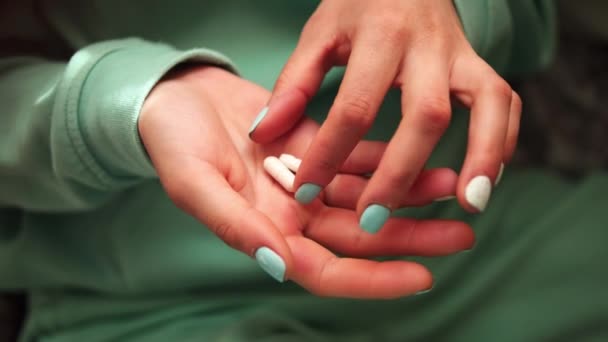 Deze beelden zijn voorzien van vrouwelijke handen close-up, met vingers die pillen uit de palm selecteren. De groene kleur van kleding en nagels verbetert de visuele impact, gericht op de interactie met de pillen. - Video