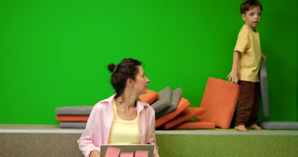 Retrato de uma mulher de negócios caucasiana sentada trabalhando online com laptop com fundo verde e criança pequena distraindo trabalho de forma materna. Imagens de alta qualidade 4k - Filmagem, Vídeo