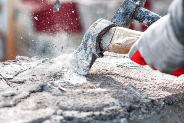 Työntekijä leikkaa sementillä kiven moukarilla. Rakennustyömaan työntekijä - Valokuva, kuva