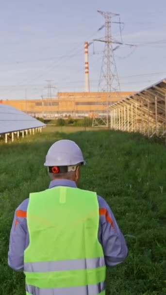 Antiguo ingeniero de construcción caminando entre paneles solares en la estación de campo ecológica. Las filas de baterías solares. Concepto de energías renovables y ecología - Metraje, vídeo