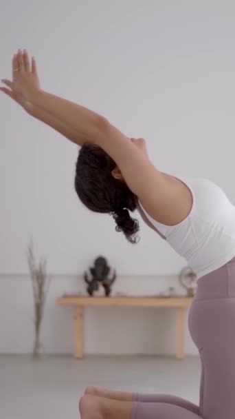 Vertical. Vista lateral latina mujer en ropa deportiva haciendo ejercicio de puente de yoga. Joven hembra concentrándose realizando pose asana rueda interior. Bienestar femenino, meditación, cuidado corporal y salud mental. - Metraje, vídeo