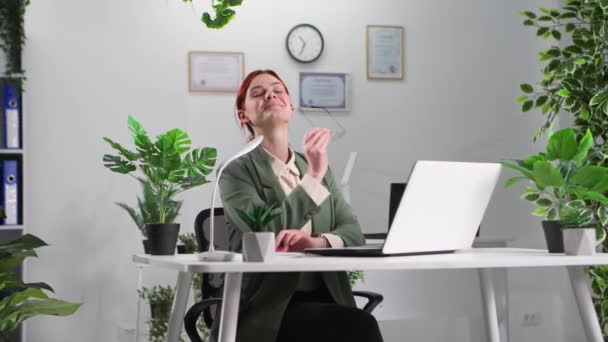 portrait d'une jeune femme souriante dans des lunettes travaillant sur un ordinateur et prenant des notes dans un bloc-notes alors qu'elle était assise à une table au bureau, souriante et regardant la caméra - Séquence, vidéo