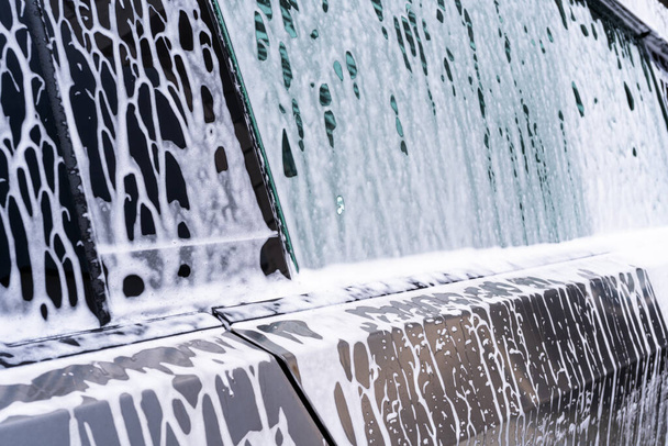 Denver, Colorado, USA-May 5, 2024-A close-up view of a Tesla Cybertruck covered in soap suds during a car wash, showing the flowing patterns over its angular surface and highlighting the unique - Φωτογραφία, εικόνα