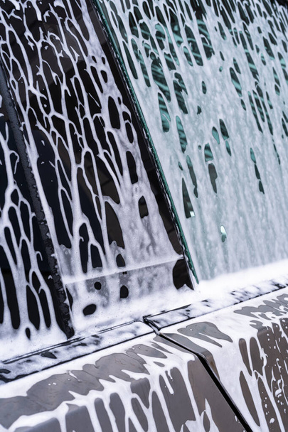 Denver, Colorado, USA-May 5, 2024-A close-up view of a Tesla Cybertruck covered in soap suds during a car wash, showing the flowing patterns over its angular surface and highlighting the unique - Φωτογραφία, εικόνα