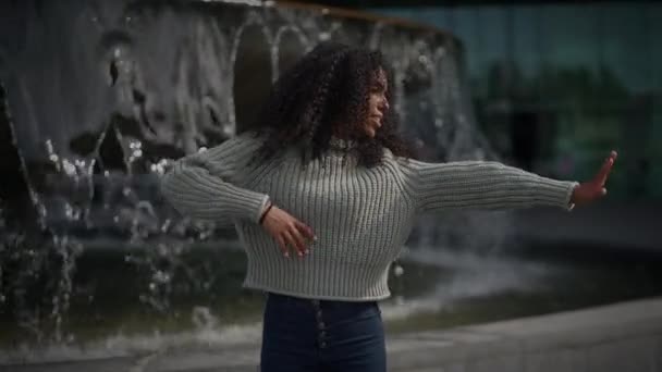 Ευτυχισμένη νεαρή γυναίκα με σγουρά μαλλιά που χορεύει στο δρόμο της πόλης σε αργή κίνηση  - Πλάνα, βίντεο