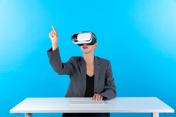 Gerente inteligente vestindo óculos VR enquanto se senta à mesa com teclado. Empresária apontando para gerenciar a análise de dados ao usar terno e fone de ouvido realidade visual e entrar em metaverso. Contrapeção. - Foto, Imagem