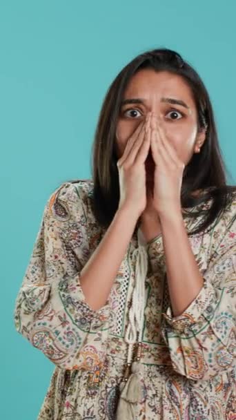 Verticale video Angstige indiaanse vrouw bedekt gezicht met handpalmen, bezorgd over de toekomst, geïsoleerd over studio-achtergrond. Spanning geschokt door verontrustend nieuws, hijgend, benauwd gevoel, camera A - Video