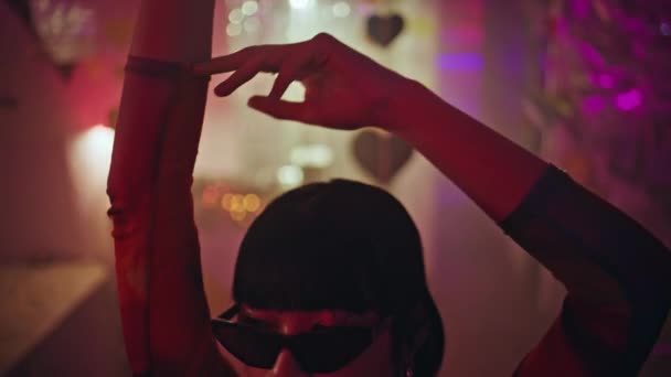 Menina legal dançando mãos em neon luz nightclub closeup. Moda moda mulher corpo em movimento no clube de discoteca com clima celebração vibrante usando óculos de sol. Chic asiático clubber desfrutar atmosférico vida noturna - Filmagem, Vídeo