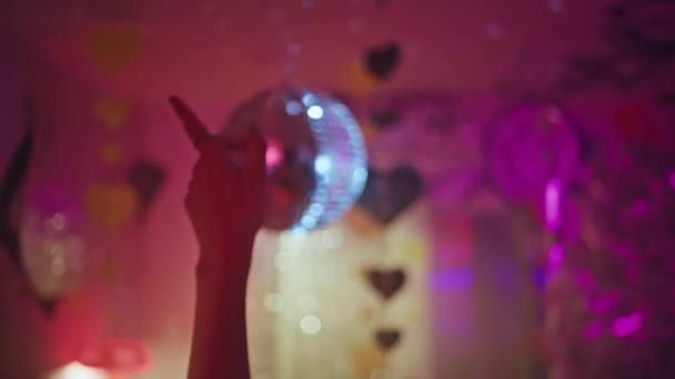 Szekrény nő kéz táncol diszkó labda alatt vibráló nightclubban. Ismeretlen lány klubos integető karok ünnepi hangulatot neon fények és szív dekoráció. A trendi bulizók élvezik az éjszakai életet.. - Felvétel, videó