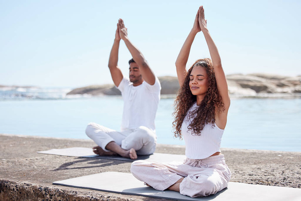 Prayer hands, yoga and couple with meditation at beach for spiritual fitness, mental wellness and namaste. Outdoor, pilates and yogi woman with man with eyes closed for mindfulness, balance or relax. - Photo, Image