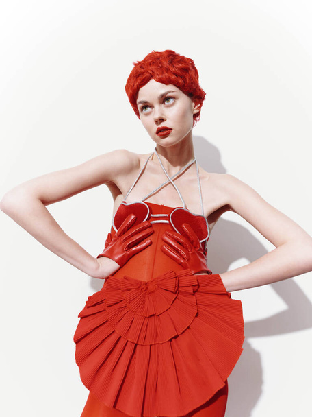 Selbstbewusste Frau in elegantem roten Kleid und Handschuhen posiert mit den Händen auf den Hüften für Kamerafahrten - Foto, Bild