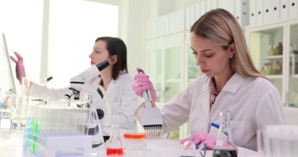 Zwei Wissenschaftler in einem Labor führen ein Experiment mit einer Mehrkanal-Pipette durch. Teamarbeit im chemisch-pharmazeutischen Labor - Filmmaterial, Video