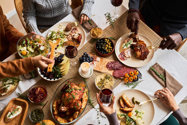 Wysoki kąt widzenia na różne grupy przyjaciół korzystających domowe jedzenie przy świątecznym stole z pieczonym indykiem lub kurczakiem, przestrzeń kopiowania - Zdjęcie, obraz