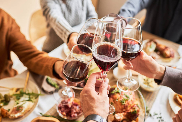 Primo piano di persone che brindano con bicchieri di vino rosso a tavola festiva, spazio per la copia - Foto, immagini