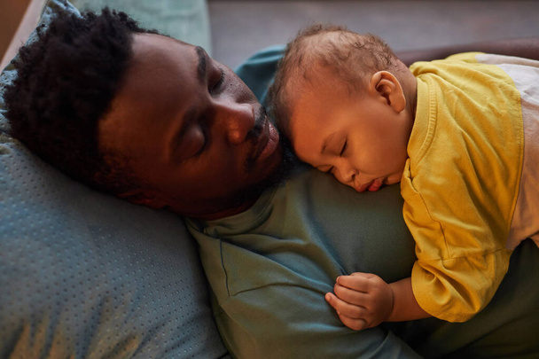 Freimütiges Porträt eines jungen Vaters und seines Sohnes beim gemeinsamen Einschlafen - Foto, Bild
