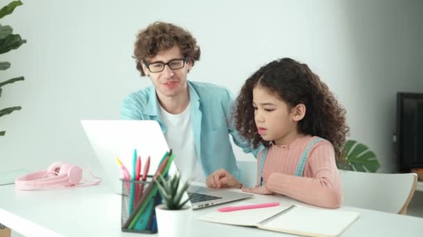 Kaukasische vader helpt of ondersteunt dochter bij het maken van huiswerk. Positieve vader kijken naar tiener schoolmeisje werken en leren op notebook, terwijl het aanmoedigen en zoeken met behulp van laptop. Pedagogie. - Video