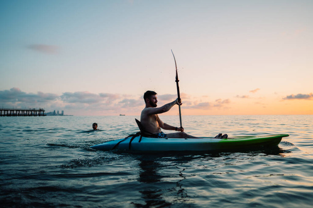 Um homem navega numa prancha SUP ao pôr-do-sol no mar. Foto de alta qualidade - Foto, Imagem