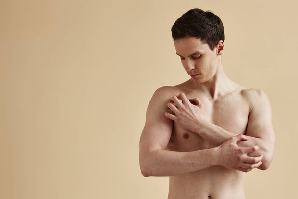 Minimal μέση μέχρι το πορτρέτο του shirtless νεαρός άνδρας ξύσιμο του δέρματος σε μπεζ φόντο, αντίγραφο χώρου - Φωτογραφία, εικόνα