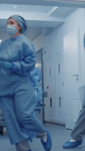 Enfermera y paramédico abren rápidamente las puertas del pasillo de las instalaciones médicas. Los cirujanos empujan la camilla con un anciano gravemente herido a la sala de operaciones. El personal médico trabaja en urgencias. Vertical - Imágenes, Vídeo