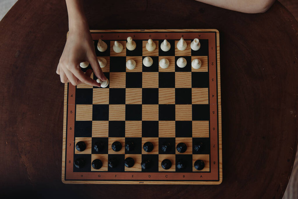 Intensa partita strategica di scacchi giocata su un classico tavolo di legno con scacchiera in bianco e nero - Foto, immagini