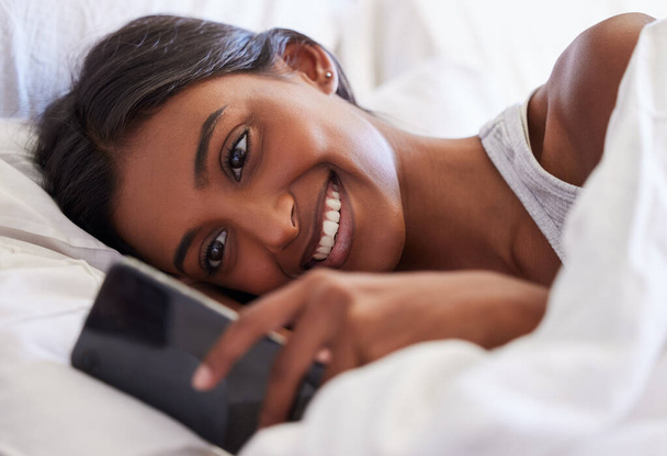 Kobieta, telefon i sms-y rano, czytanie i budzenie z uśmiechem na powiadomienie, czat lub randki online w domu. Dziewczyna, osoba i zadowolony ze smartfona, aplikacji i sieci komórkowej w sypialni. - Zdjęcie, obraz