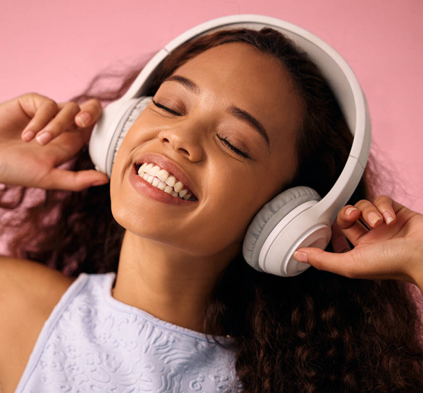 Dziewczyna, relaks i słuchanie muzyki ze słuchawkami do jazzu lub bije na różowym tle studio. Szczęśliwa kobieta korzystających podcast, strumieniowe audio lub dźwięk z uśmiechem dla radia, piosenki lub listy odtwarzania. - Zdjęcie, obraz