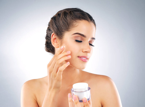 Relax, face cream and jar with woman in studio for skincare, application or beauty with cosmetics. Female model, lotion or moisturizer by white background for wellness shine, facial treatment or glow. - Photo, Image