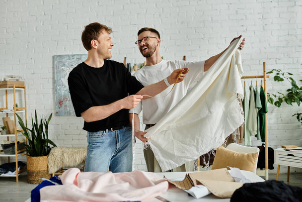 Due uomini stanno fianco a fianco in un laboratorio di design, discutendo e realizzando abbigliamento alla moda. - Foto, immagini