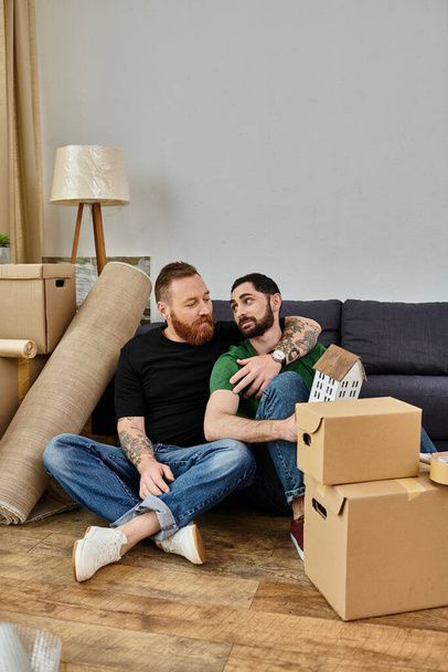 A gay couple relaxes on top of a couch in their new home filled with moving boxes, beginning a new chapter in their lives. - Foto, afbeelding