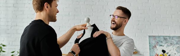 Due uomini alla moda, una coppia gay innamorata, stanno fianco a fianco, immersi nella creazione di abbigliamento alla moda in un laboratorio di design. - Foto, immagini