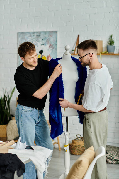 Két férfi megvizsgál egy divatos kék inget, ami egy próbababán látható egy tervező műhelyben.. - Fotó, kép